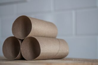 Closeup of stacked brown cardboard tubes of finished toilet paper placed on wooden table