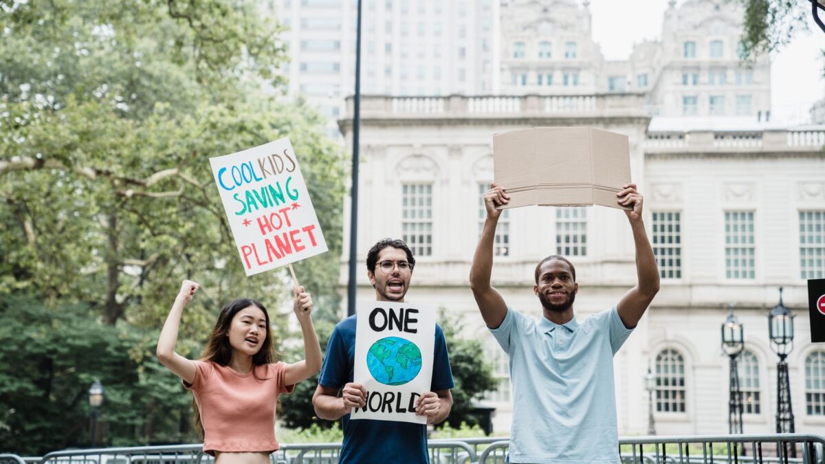Young activists holding climate change signs in a city protest rally outdoors.